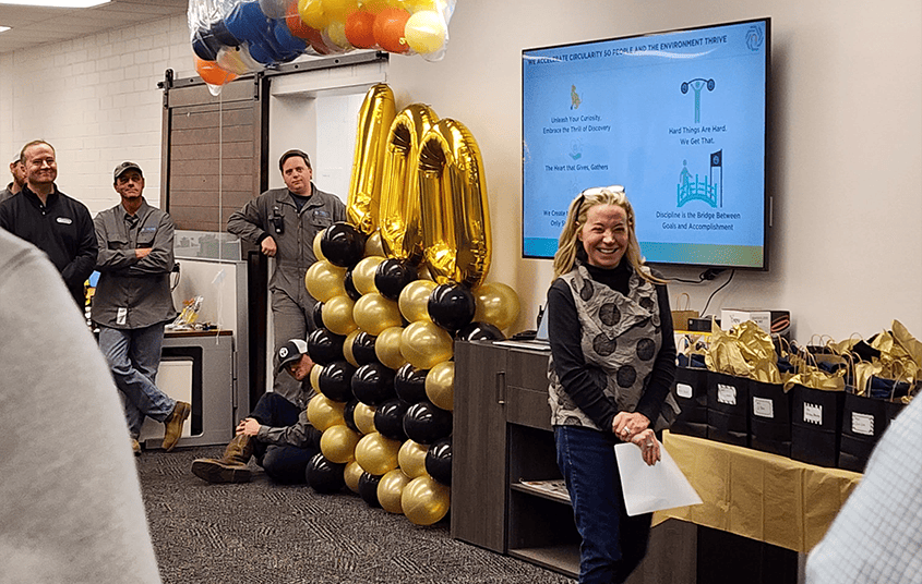 Nexus Circular employees gathered at a company celebration with gold and black '100' balloons