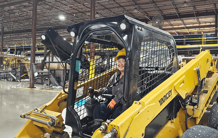 Nexus Circular employee in a hard hat driving heavy machinery inside the plant