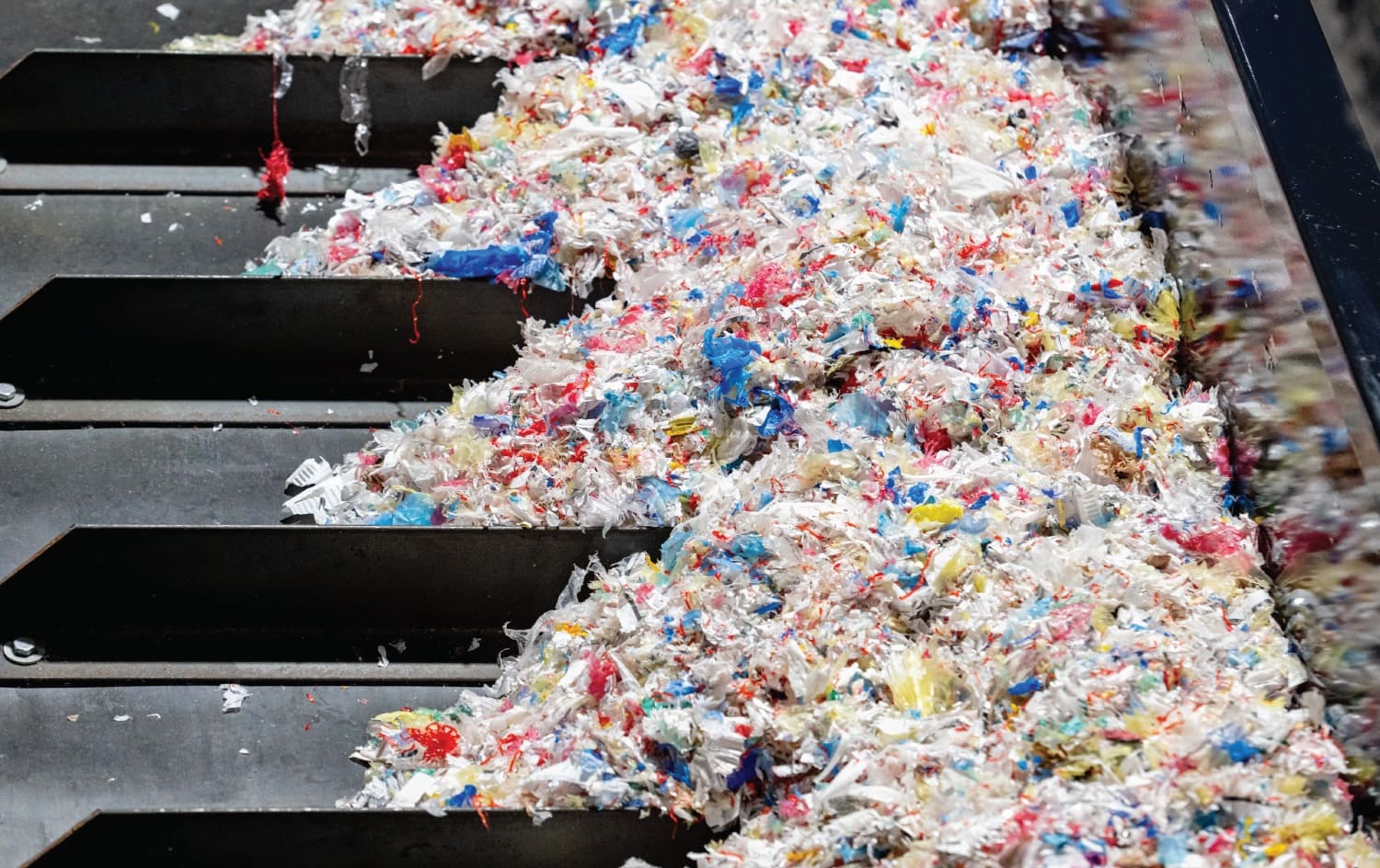 Shredded, multicolored plastic film piled on a conveyor at the Nexus Circular recycling facility